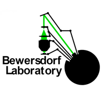 Logo that says Bewersdorf Laboratory on the bottom in black text with a simple microscope setup above the text in the middle that extends from a black circle on the bottom right.