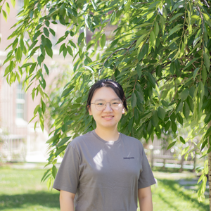 headshot of yuan tian, east asian woman with black hair pulled back and glasses in grey t shirt smiling at the camera