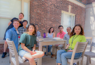 9 lab members sit around a wooden table smiling at the camera